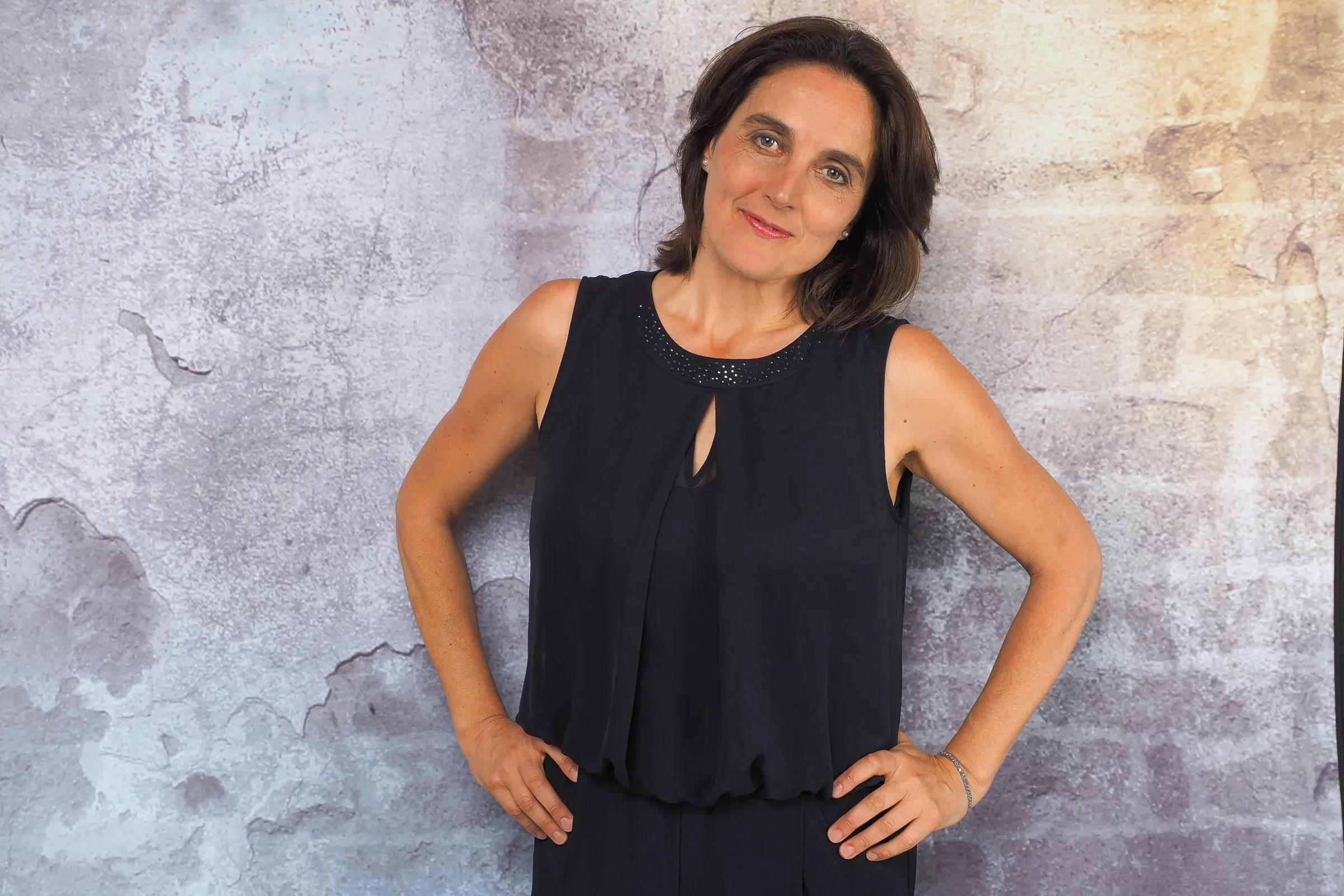Ina Haferkorn im schwarzen Kleid vor einer grauen Wand